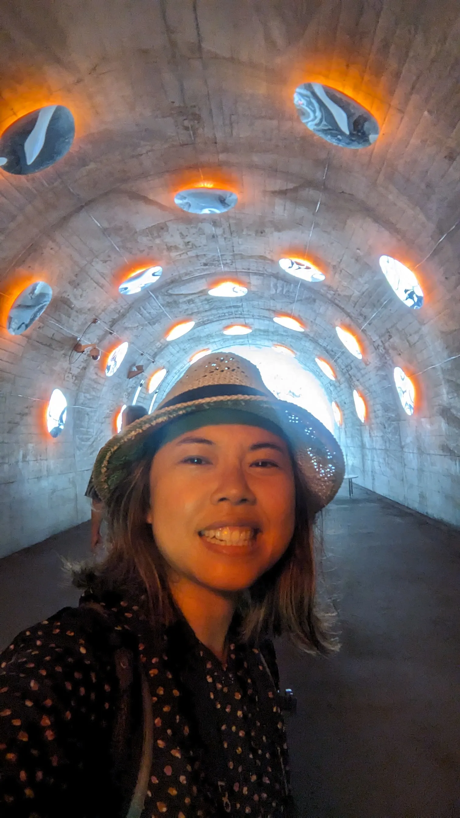 Sin Ko smiling in a hat inside an illuminated tunnel